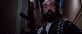 Movie still from “Die Hard” (1988), directed by John McTiernan – A man with a beard holding an electric guitar; Close Up shot, Low angle