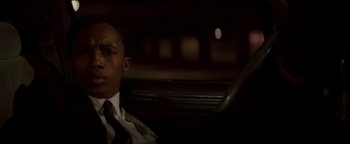 Movie still from “Die Hard” (1988), directed by John McTiernan – A man sitting in the back seat of a car at night; Close Up shot, Low angle