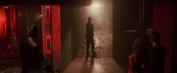 Movie still from “Die Hard” (1988), directed by John McTiernan – A man standing in a dark hallway with a light shining on him; Wide shot, Low angle