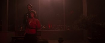 Movie still from “Die Hard” (1988), directed by John McTiernan – A man and a woman standing in front of an audience; Wide shot, Low angle