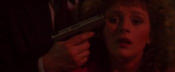 Movie still from “Die Hard” (1988), directed by John McTiernan – A woman holding a gun up to her face; Close Up shot, High angle