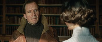 Movie still from “The King's Man” (2021), directed by Matthew Vaughn – An older man wearing a sweater and a jacket talking to an older woman; Close Up shot, Over the shoulder angle