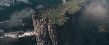 Movie still from “The King's Man” (2021), directed by Matthew Vaughn – A large cliff with a green grass covered hillside; Extreme Wide shot, High angle