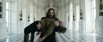 Movie still from “The King's Man” (2021), directed by Matthew Vaughn – A man holding a young child in a room; Medium shot, Low angle