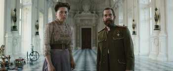 Movie still from “The King's Man” (2021), directed by Matthew Vaughn – A man and a woman standing next to each other in front of a building; Medium shot, Low angle