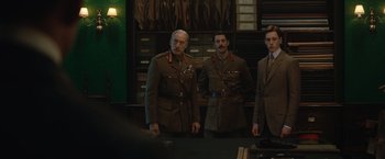 Movie still from “The King's Man” (2021), directed by Matthew Vaughn – A group of men standing next to each other in a room; Medium shot, Low angle