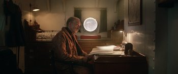 Movie still from “The King's Man” (2021), directed by Matthew Vaughn – An older man sitting at a desk in front of a window; Medium shot, Low angle