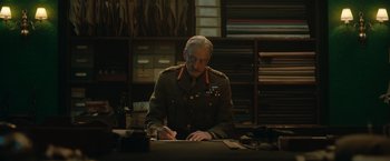 Movie still from “The King's Man” (2021), directed by Matthew Vaughn – An older man in a military uniform writing on a paper; Medium shot, Low angle