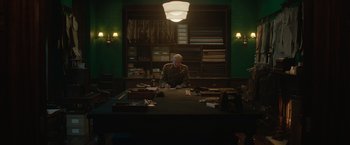 Movie still from “The King's Man” (2021), directed by Matthew Vaughn – A man sitting at a desk in a room; Wide shot, Low angle