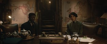 Movie still from “The King's Man” (2021), directed by Matthew Vaughn – Two people sitting at a table in front of a map; Medium shot, High angle