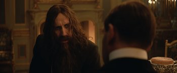 Movie still from “The King's Man” (2021), directed by Matthew Vaughn – A man with long hair and a beard talking to another man in a suit; Close Up shot, Over the shoulder angle