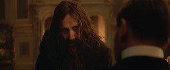 Movie still from “The King's Man” (2021), directed by Matthew Vaughn – A man with long hair and a long beard; Close Up shot, Over the shoulder angle