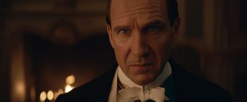 Movie still from “The King's Man” (2021), directed by Matthew Vaughn – A person wearing a suit and bow tie; Close Up shot, Over the shoulder angle