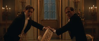Movie still from “The King's Man” (2021), directed by Matthew Vaughn – Two men in black suits holding onto a box; Medium shot, Low angle