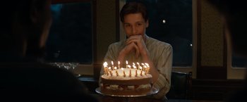 Movie still from “The King's Man” (2021), directed by Matthew Vaughn – A man sitting in front of a birthday cake; Medium shot, High angle