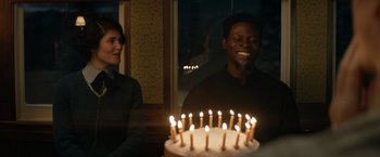 Movie still from “The King's Man” (2021), directed by Matthew Vaughn – A man and a woman sitting in front of a cake with lit candles on it; Medium shot, Over the shoulder angle