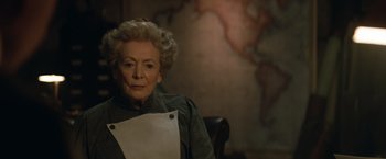 Movie still from “The King's Man” (2021), directed by Matthew Vaughn – An older woman sitting in a chair holding a piece of paper; Close Up shot, High angle