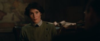 Movie still from “The King's Man” (2021), directed by Matthew Vaughn – A woman in a green dress is looking at the camera; Close Up shot, Over the shoulder angle