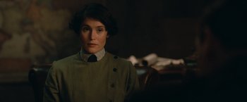 Movie still from “The King's Man” (2021), directed by Matthew Vaughn – A woman in a green coat and a black tie; Close Up shot, Over the shoulder angle