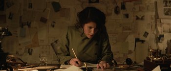 Movie still from “The King's Man” (2021), directed by Matthew Vaughn – A woman is writing on a piece of paper; Medium shot, Low angle