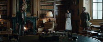 Movie still from “The King's Man” (2021), directed by Matthew Vaughn – A person in a living room with a book case; Wide shot, Low angle
