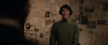 Movie still from “The King's Man” (2021), directed by Matthew Vaughn – A woman standing in front of a wall covered with papers; Medium shot, Over the shoulder angle