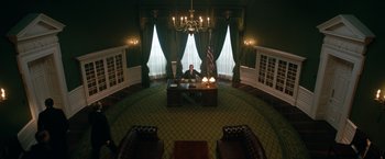 Movie still from “The King's Man” (2021), directed by Matthew Vaughn – A man sitting at a desk in front of a large window; Wide shot, High angle