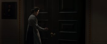 Movie still from “The King's Man” (2021), directed by Matthew Vaughn – A woman opening a door in a dark room; Medium shot, High angle