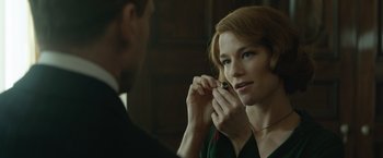 Movie still from “The King's Man” (2021), directed by Matthew Vaughn – A woman putting on a necklace in front of a mirror; Close Up shot, Over the shoulder angle