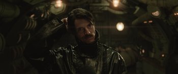 Movie still from “The King's Man” (2021), directed by Matthew Vaughn – A man with a beard and mustache wearing a black jacket; Close Up shot, Over the shoulder angle
