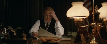 Movie still from “The King's Man” (2021), directed by Matthew Vaughn – A man sitting at a table with a plate of cookies; Medium shot, Over the shoulder angle