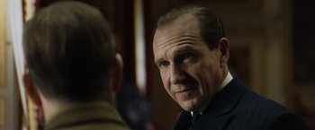 Movie still from “The King's Man” (2021), directed by Matthew Vaughn – A person wearing a suit and tie; Close Up shot, Over the shoulder angle