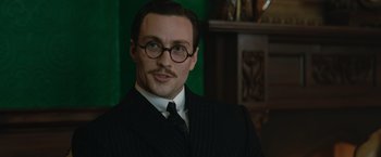 Movie still from “The King's Man” (2021), directed by Matthew Vaughn – A man in a suit and tie wearing glasses; Close Up shot, Low angle