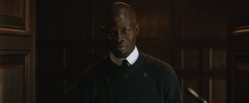 Movie still from “The King's Man” (2021), directed by Matthew Vaughn – A man in a black sweater and a white shirt; Close Up shot, Low angle