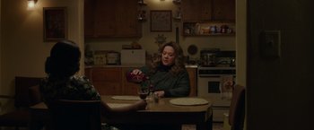 Movie still from “The Kitchen” (2019), directed by Andrea Berloff – A woman sitting at a table in a kitchen; Medium shot, High angle