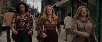 Movie still from “The Kitchen” (2019), directed by Andrea Berloff – A woman is walking down the street with a brown purse; Medium shot, Low angle