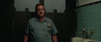 Movie still from “The Kitchen” (2019), directed by Andrea Berloff – A man in a uniform standing in front of a wall; Close Up shot, Over the shoulder angle