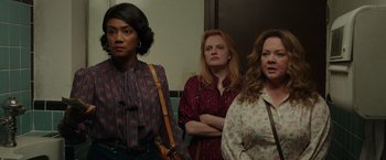 Movie still from “The Kitchen” (2019), directed by Andrea Berloff – A group of women standing next to each other in a room; Medium shot, Over the shoulder angle