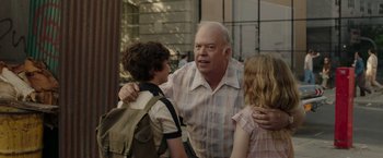 Movie still from “The Kitchen” (2019), directed by Andrea Berloff – An older man is talking to two young children; Medium shot, Over the shoulder angle
