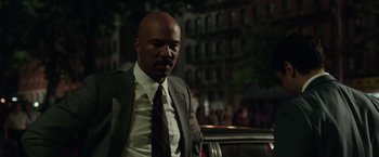 Movie still from “The Kitchen” (2019), directed by Andrea Berloff – A man wearing a suit and tie standing next to a car; Medium shot, Over the shoulder angle