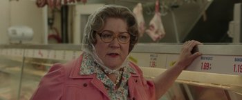 Movie still from “The Kitchen” (2019), directed by Andrea Berloff – An older woman wearing a pink jacket and a floral head scarf; Close Up shot, Over the shoulder angle