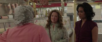 Movie still from “The Kitchen” (2019), directed by Andrea Berloff – A woman in a floral shirt talking to a woman in a pink dress; Medium shot, Over the shoulder angle