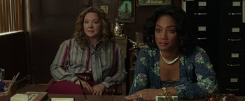 Movie still from “The Kitchen” (2019), directed by Andrea Berloff – Two women sitting at a table in front of a mirror; Medium shot, Over the shoulder angle