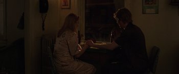 Movie still from “The Kitchen” (2019), directed by Andrea Berloff – A man and a woman sitting at a table holding hands; Medium shot, High angle
