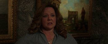 Movie still from “The Kitchen” (2019), directed by Andrea Berloff – An older woman with long hair and a necklace; Medium shot, Over the shoulder angle