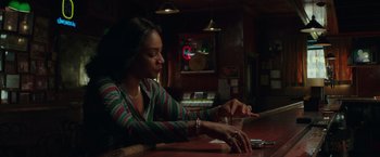 Movie still from “The Kitchen” (2019), directed by Andrea Berloff – A woman sitting at a table with a glass of wine; Medium shot, Low angle