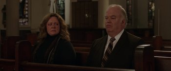 Movie still from “The Kitchen” (2019), directed by Andrea Berloff – A man and a woman sitting in a church pew; Medium shot, Over the shoulder angle