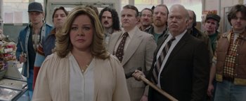 Movie still from “The Kitchen” (2019), directed by Andrea Berloff – A group of men and a woman holding a wooden axe; Medium shot, Over the shoulder angle