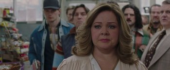 Movie still from “The Kitchen” (2019), directed by Andrea Berloff – A woman standing in front of a group of people; Close Up shot, Over the shoulder angle