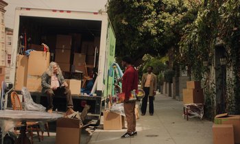 A man standing next to a moving truck on the sidewalk